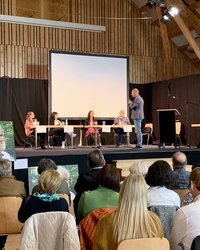 Besucher:innen verfolgen die Diskussion auf der Bühne